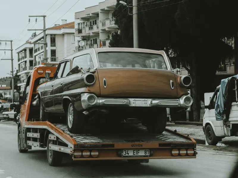 Stari automobil učvršćen na platformi šlep vozila na gradskoj ulici
